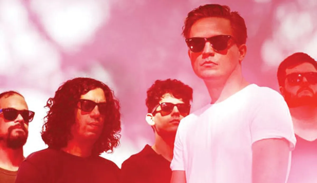 Photo of five men wearing sunglasses, the band Merchandise, washed out in shades of red.