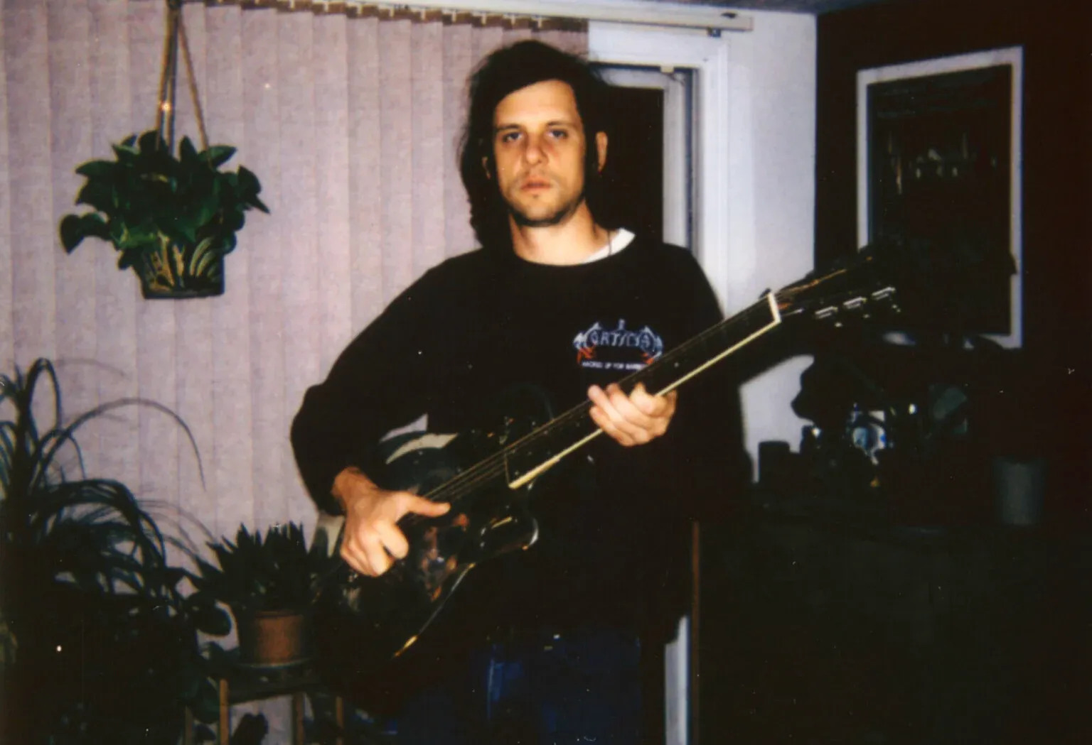 Polaroid photo of Ryan Davis, slightly out of focus, holding a guitar in a dimly lit room.